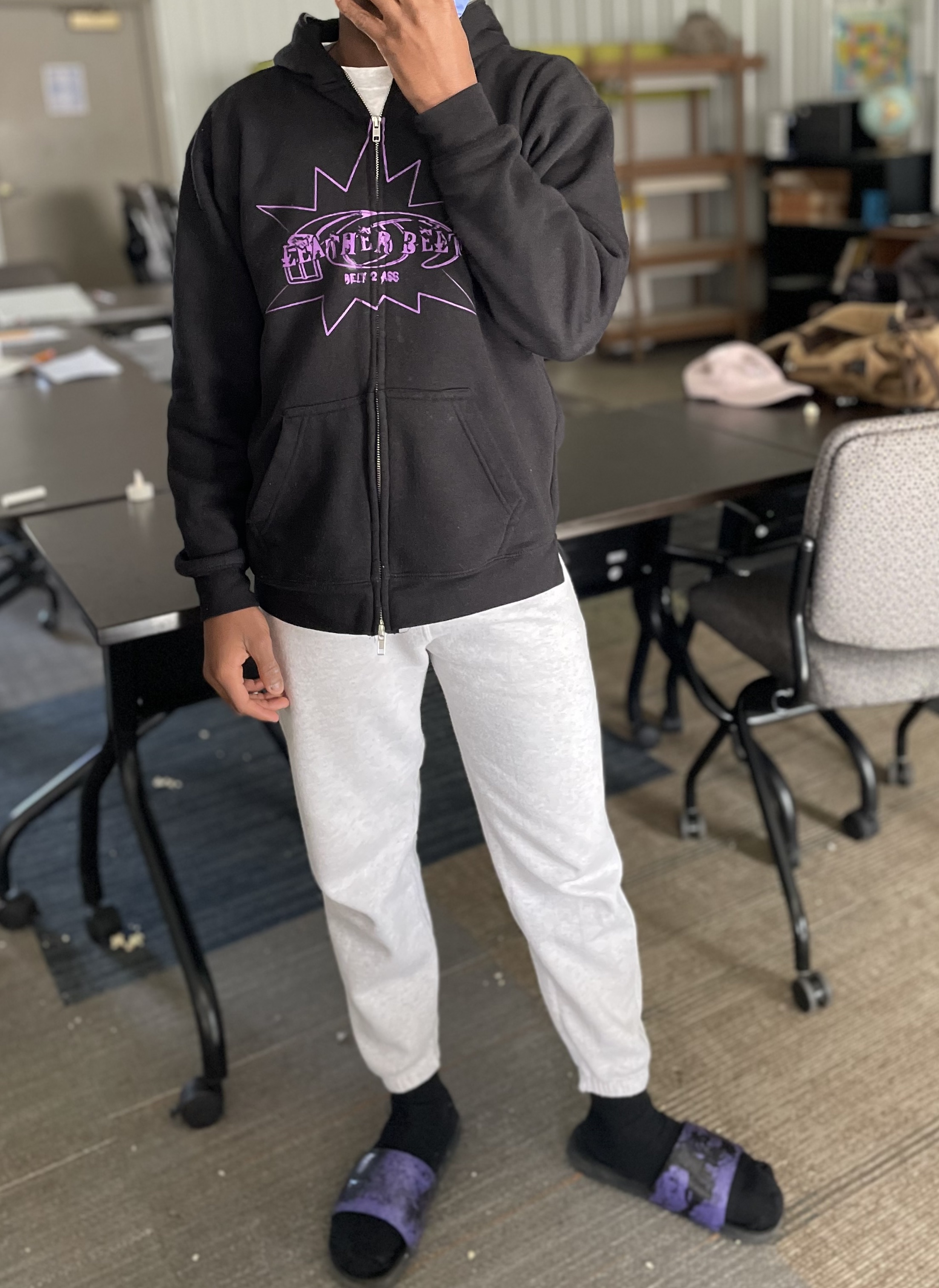 Student posing with their "Leather Belt" branded sweatshirt and slides