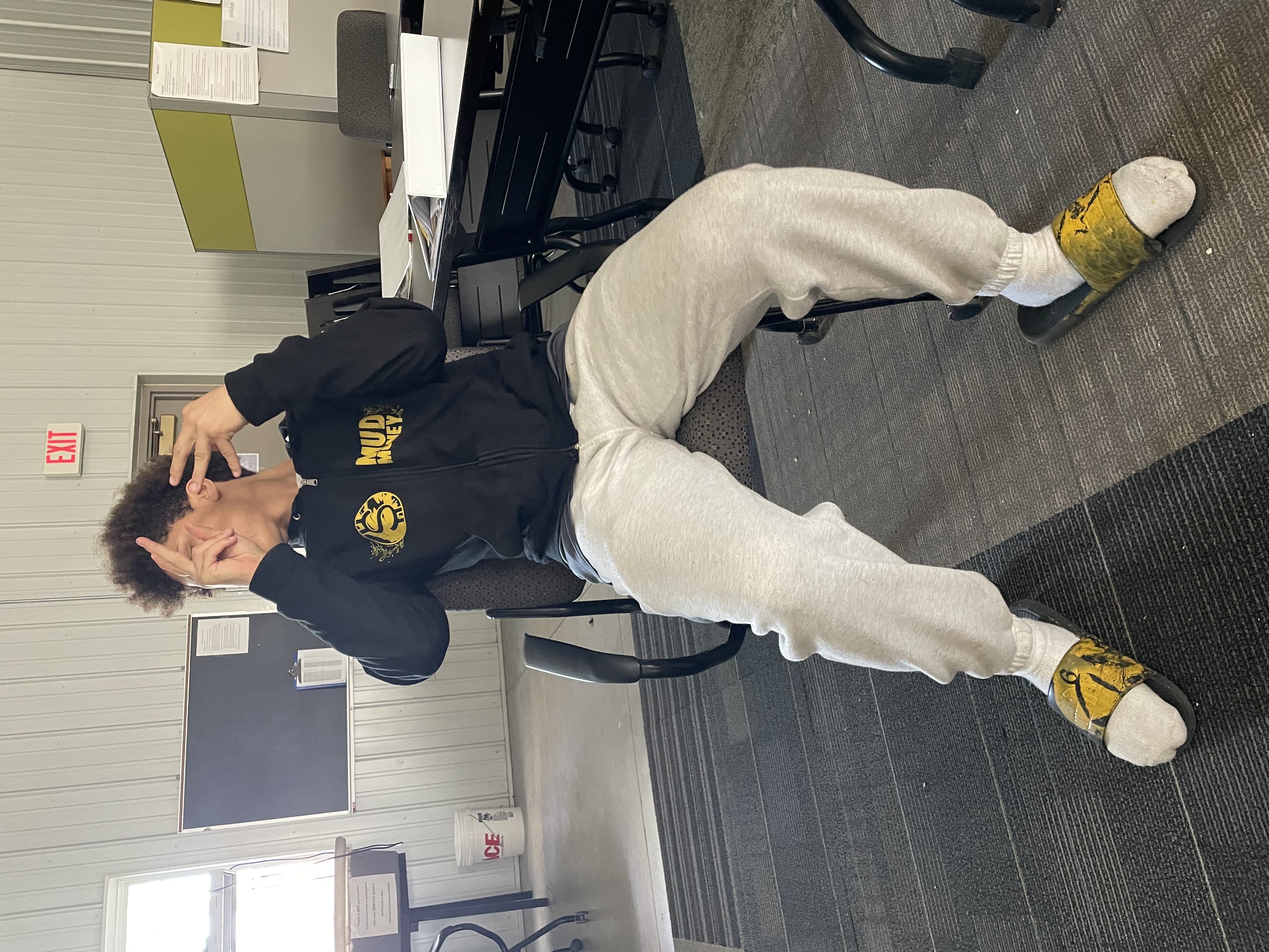Student posing with their new "Mud Money" personal branded sweatshirt and slides