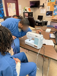 Jail students working together on the sewing machine.