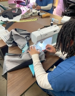 Jail student using a sewing machine in the classroom to create a final draft graduation gown.